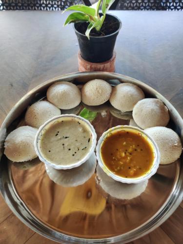 a plate of food with two bowls of dipping sauce at Sunset Valley Kerala Pool Resort - Monsoon Forest Cottage Stay in Idukki with Private Waterfalls, Natural Streams & Breathtaking Views in Pīrmed