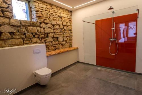 een badkamer met een toilet en een bakstenen muur bij Ferienhaus ScheunenRefugio in Rot am See
