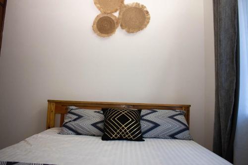 1 cama con 2 almohadas contra una pared blanca en Missy Hidden gem, en Mombasa