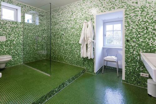 een groene betegelde badkamer met een douche en een wastafel bij Alte Schule in Herrentierbach