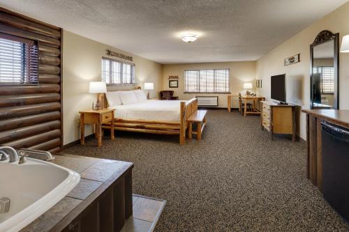 Stoney Creek Hotel Moline في مولين: غرفة نوم بسرير وحمام مع حوض استحمام