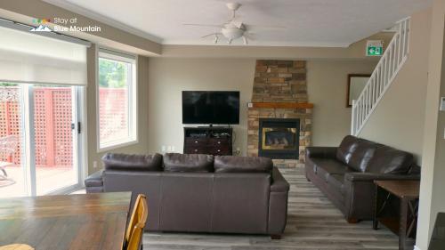 a living room with two leather couches and a fireplace at 5 Bedrooms, Mountain Views, Steps from Blue Mountain Village, Hot Tub, BBQ in Blue Mountains