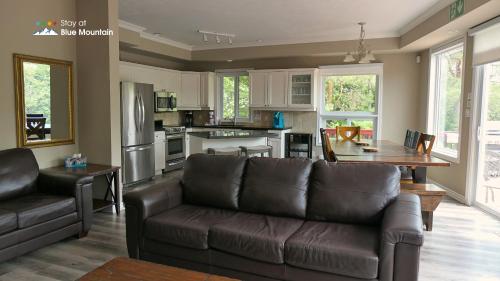 a living room with a couch and a kitchen at 5 Bedrooms, Mountain Views, Steps from Blue Mountain Village, Hot Tub, BBQ in Blue Mountains