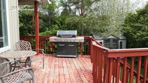 a grill on a deck with a table and chairs at 5 Bedrooms, Mountain Views, Steps from Blue Mountain Village, Hot Tub, BBQ in Blue Mountains