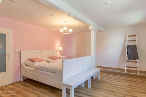 a bedroom with a white bed and a bench at Ferienhaus S`bunde Heisle in Blaufelden