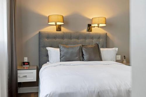 a bedroom with a large white bed with two lamps at Hotel Port-Royal in Quebec City