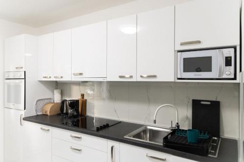 a white kitchen with a sink and a microwave at Maris in Osijek