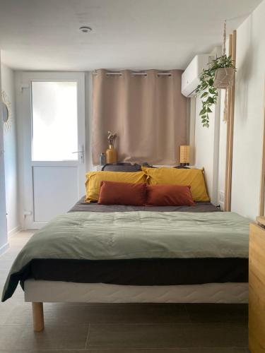 a bedroom with a large bed with yellow and orange pillows at Le Petit Studio in Avignon