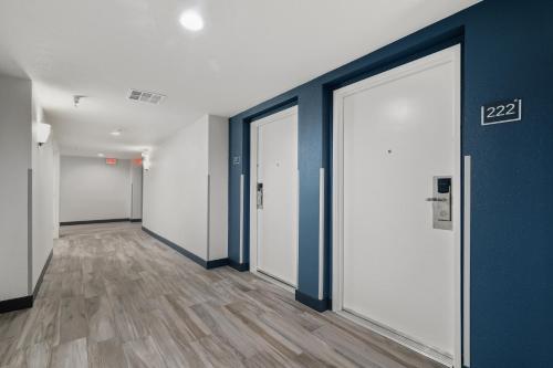 an empty hallway with white doors and wood floors at Studio 6 Suites Perris, CA in Perris