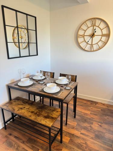 a dining room table with chairs and a clock on the wall at Spanish City View 2, Luxury Sea Front Apartment Free Onsite Parking in Whitley Bay