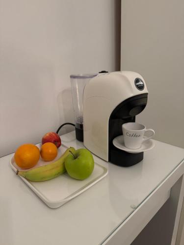 a coffee maker and a plate of fruit on a counter at Luxury Cottage Room in London