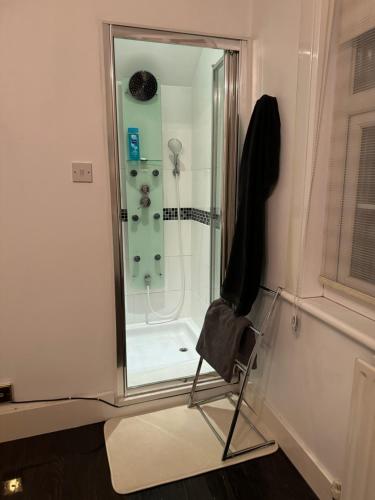 a bathroom with a shower with a chair in front of it at Luxury Cottage Room in London