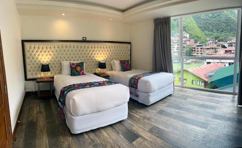 una camera d'albergo con due letti e una grande finestra di Jaya Machu Picchu Boutique Hotel a Machu Picchu