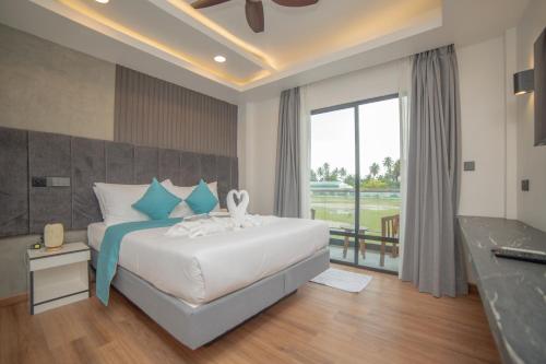 a bedroom with a large bed and a large window at Whaleshark Beach in Dhigurah