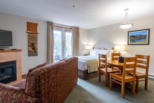 a hotel room with a bed and a table and chairs at Sundance Lodge in Sun Peaks