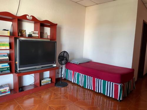 a living room with a flat screen tv and a fan at Casa Robles - Your Stay Near Airport in Managua