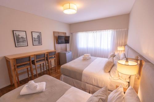 a hotel room with two beds and a table at El Misti Coliving Obelisco in Buenos Aires