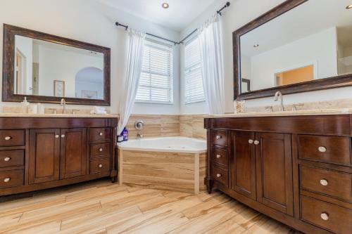 a bathroom with two sinks and a tub and two mirrors at Miami Getaway Heated Pool Villa with Mini Golf & BBQ in Miami