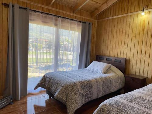a bedroom with two beds and a large window at Comodidad y hermosa vista volcán in Melipeuco