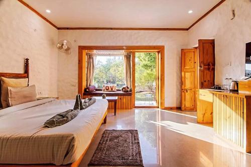 a bedroom with a large bed and a kitchen at Mandaal Corbett in Rāmnagar