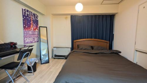 een kleine slaapkamer met een bed, een bureau en een spiegel bij Space Minami 4jo - Vacation STAY 15808 in Sapporo