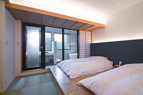 a bedroom with two beds and a large window at KyotoGosyonishi - Vacation STAY 22739v in Kyoto