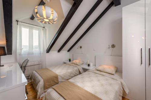 Cette chambre comprend 2 lits dans un dortoir doté de murs blancs et d'un lustre. dans l'établissement Humac Infinity Vero Apartments, à Donji Humac