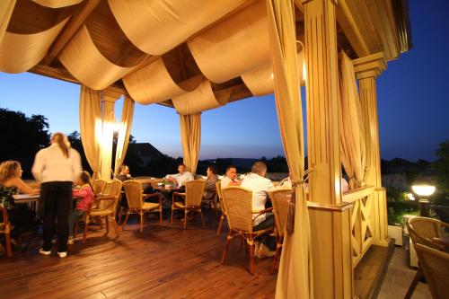a group of people sitting at tables on a deck at night at Hotel Clasic in Sebeş