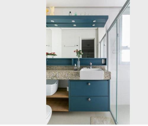 uma casa de banho com um lavatório azul e um espelho. em Duplex vista para o mar na praia dos Açores em Florianópolis