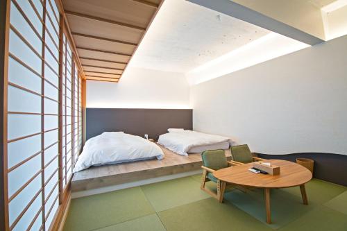 1 dormitorio con 1 cama, mesa y sillas en KyotoGosyonishi - Vacation STAY 22999v en Kyoto
