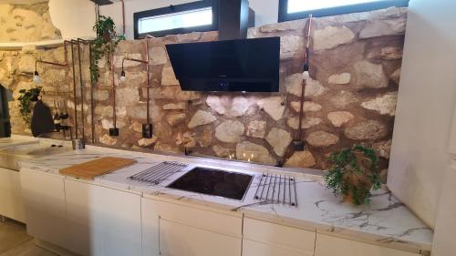 a kitchen with a tv on a stone wall at CASA CUEVA A-TIPICA in Pegalajar