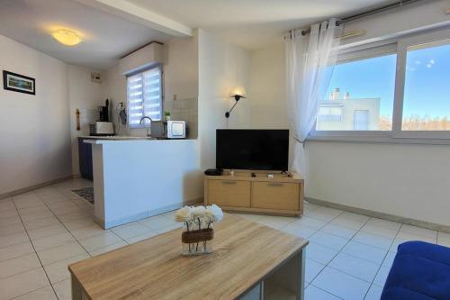 uma sala de estar com uma televisão e uma mesa em Lovely spacious nest in Port Fréjus em Fréjus