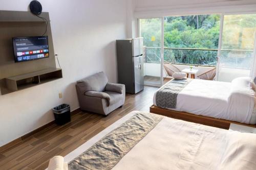 a bedroom with two beds and a tv and a chair at Lofts Terra Nuevo Vallarta in Nuevo Vallarta