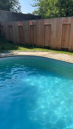 une piscine d'eau bleue devant une clôture en bois dans l'établissement La Bourgeoise, à Neuvic