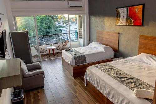 a hotel room with two beds and a balcony at Lofts Terra Nuevo Vallarta in Nuevo Vallarta