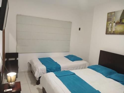 Hotel Mykonos Manta في مانتا: سريرين في غرفة الفندق باللونين الأزرق والأبيض