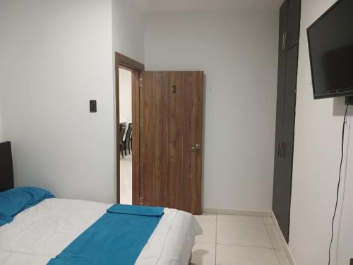 een slaapkamer met een bed en een houten deur bij Hotel Mykonos Manta in Manta