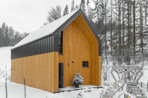 a wooden building in the snow with a swing at Hill & Chill Kudowa Zdrój in Kudowa-Zdrój