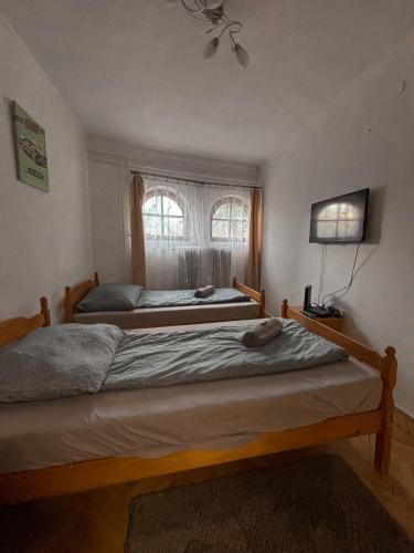 two beds in a bedroom with a window at Omega Apartman in Miskolc