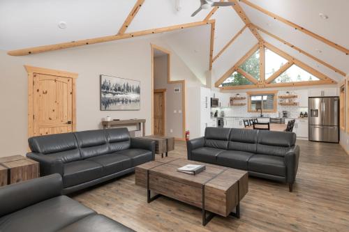 a living room with black leather furniture and a kitchen at Lazy Moose in Valemount