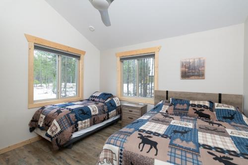 two beds in a bedroom with two windows at Lazy Moose in Valemount