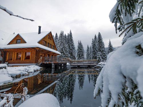 a log cabin in the snow next to a lake at Rezort pri jazere Podbanské in Pribylina