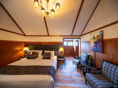 een hotelkamer met een bed, een bank en een kroonluchter bij Hana Lodge in Rotorua
