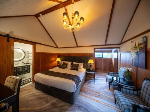 a bedroom with a large bed and a chandelier at Hana Lodge in Rotorua