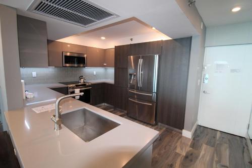 a kitchen with a sink and a refrigerator at Castle BTH2 Stunning Oceanfront Townhouse, Private Beach Access, Private Pool Access, Tennis and Free Parking! in Miami Beach