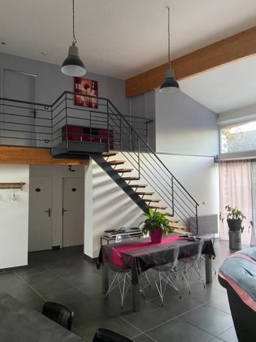 uma sala de estar com uma escada e uma mesa com uma toalha de mesa vermelha em La grange de Céline 