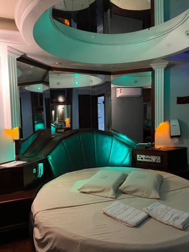 Espacial Motel في أراساتوبا: غرفة نوم مع سرير وطاولة خضراء للرأس