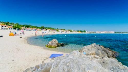 a beach with a group of people and the ocean at Les pieds dans le sable in Argelès-sur-Mer