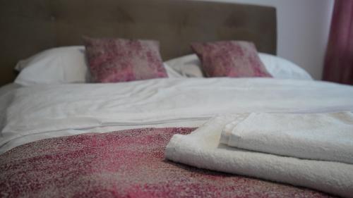 a bed with white sheets and pink pillows at Hotel Muška voda in Kladanj