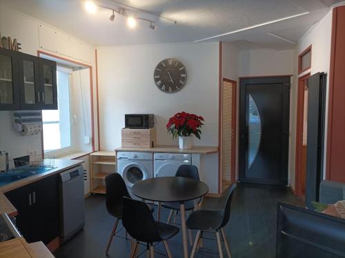 eine Küche mit einem Tisch und Stühlen sowie einer Uhr an der Wand in der Unterkunft Marguerite in Bussang